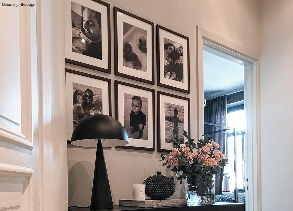 Zid sa fotografijama u hodniku, crno-bijele fotografije u tamnim okvirima